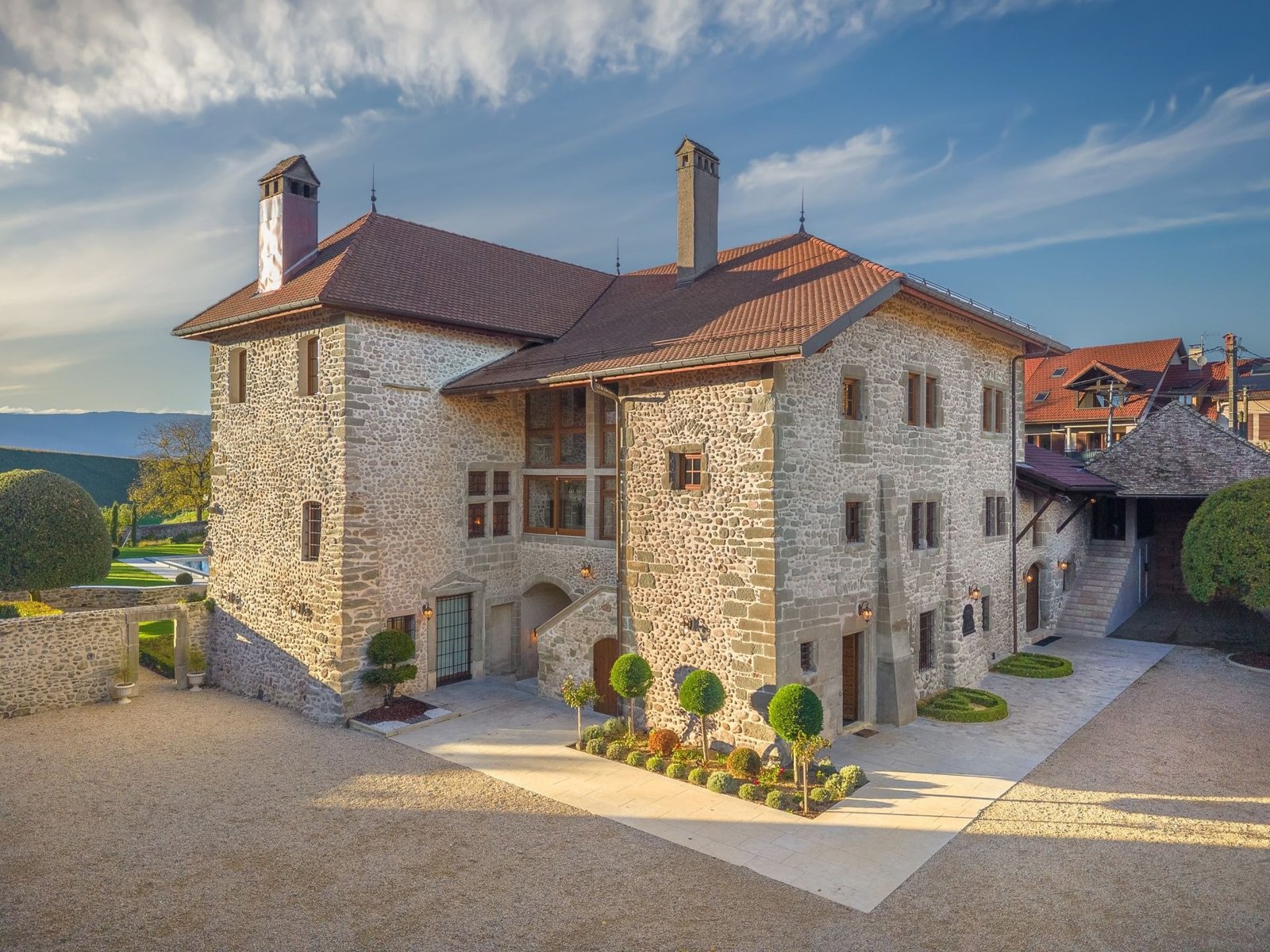 Château à louer près de Genève — façade en pierre de galets et cour d'honneur