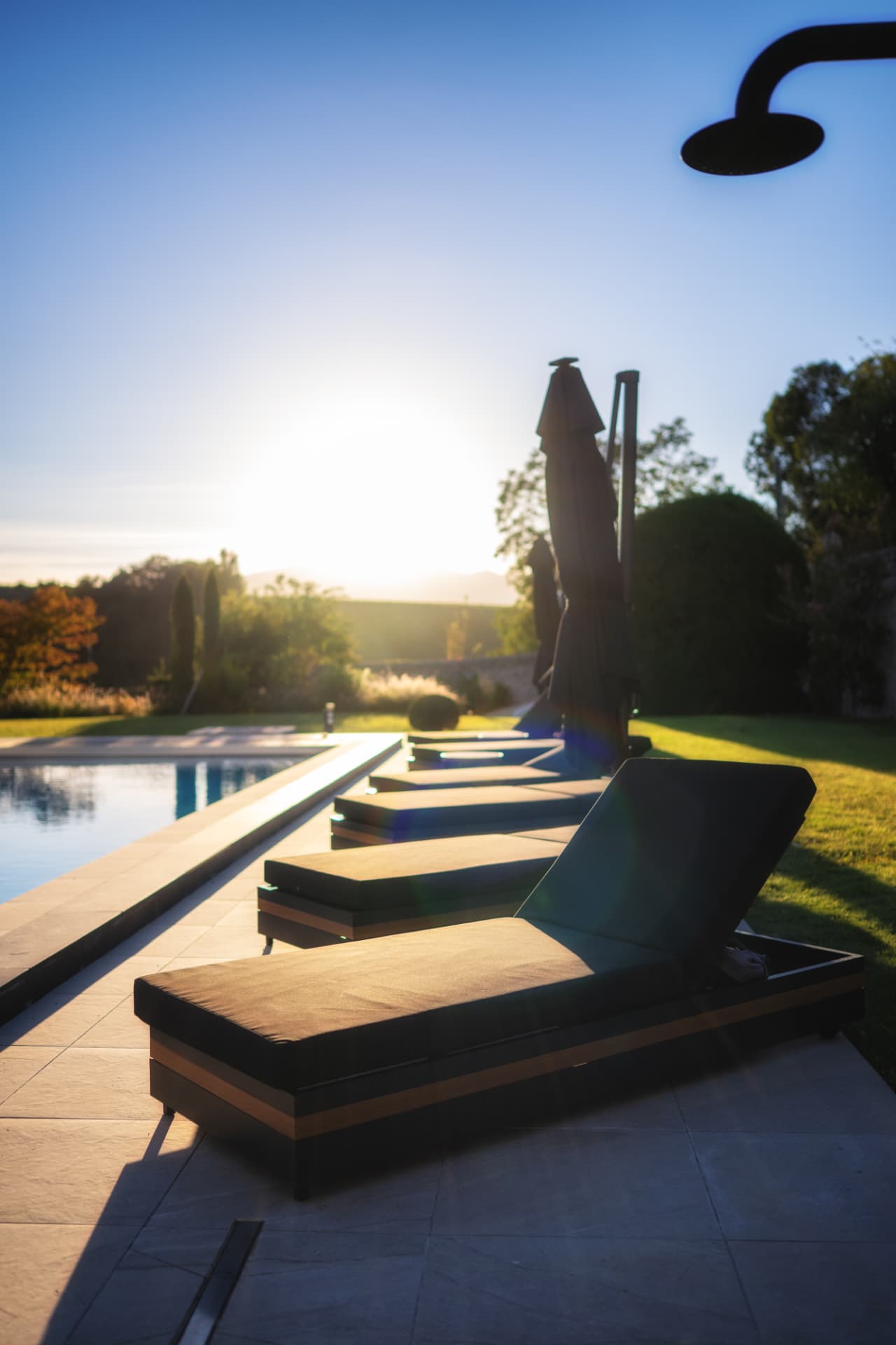 Transats alignés au bord de la piscine chauffée au soleil couchant, Château de Crâche