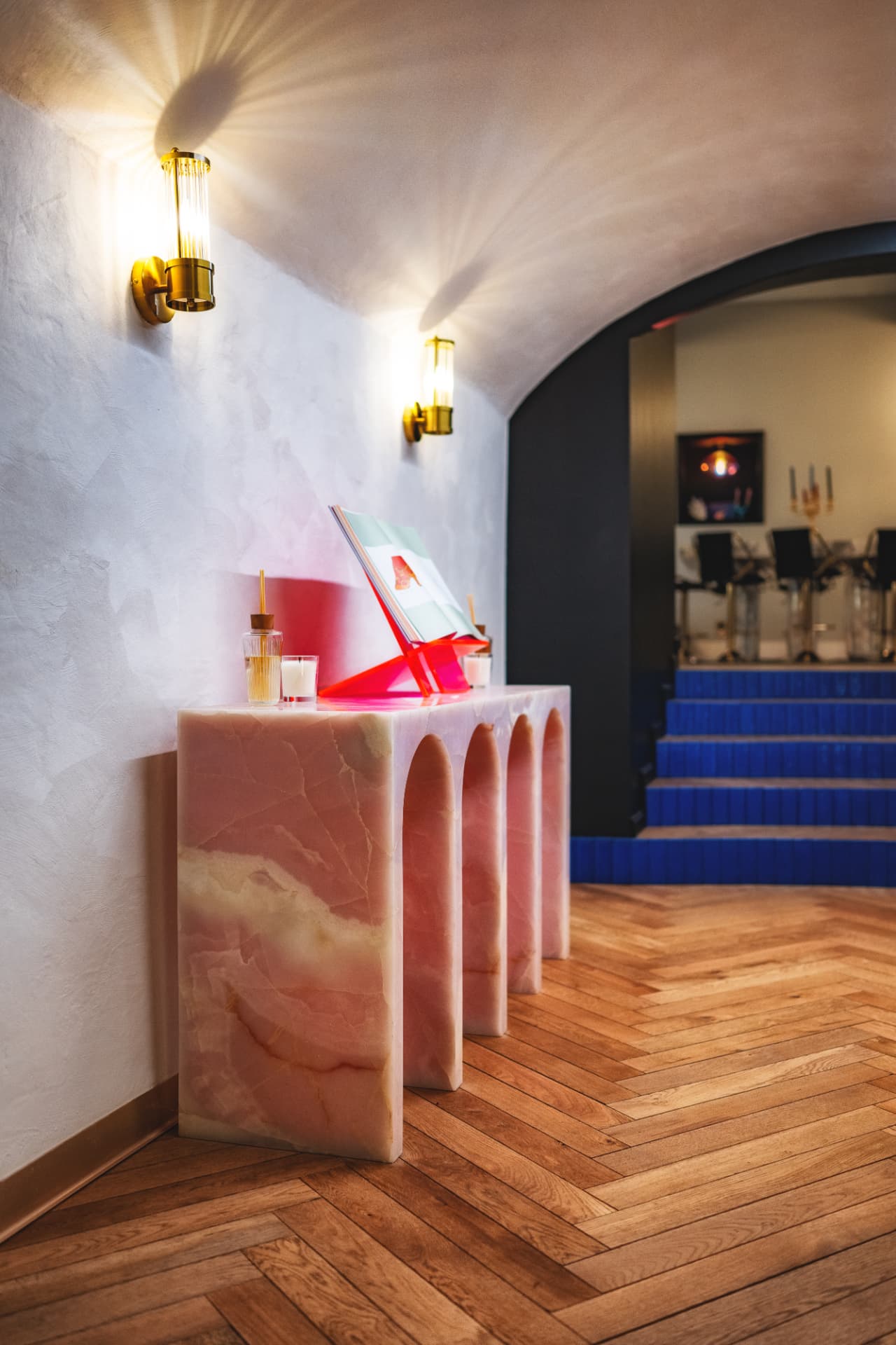 Console en onyx rose sous une voûte blanche, escalier de céramique bleue au fond