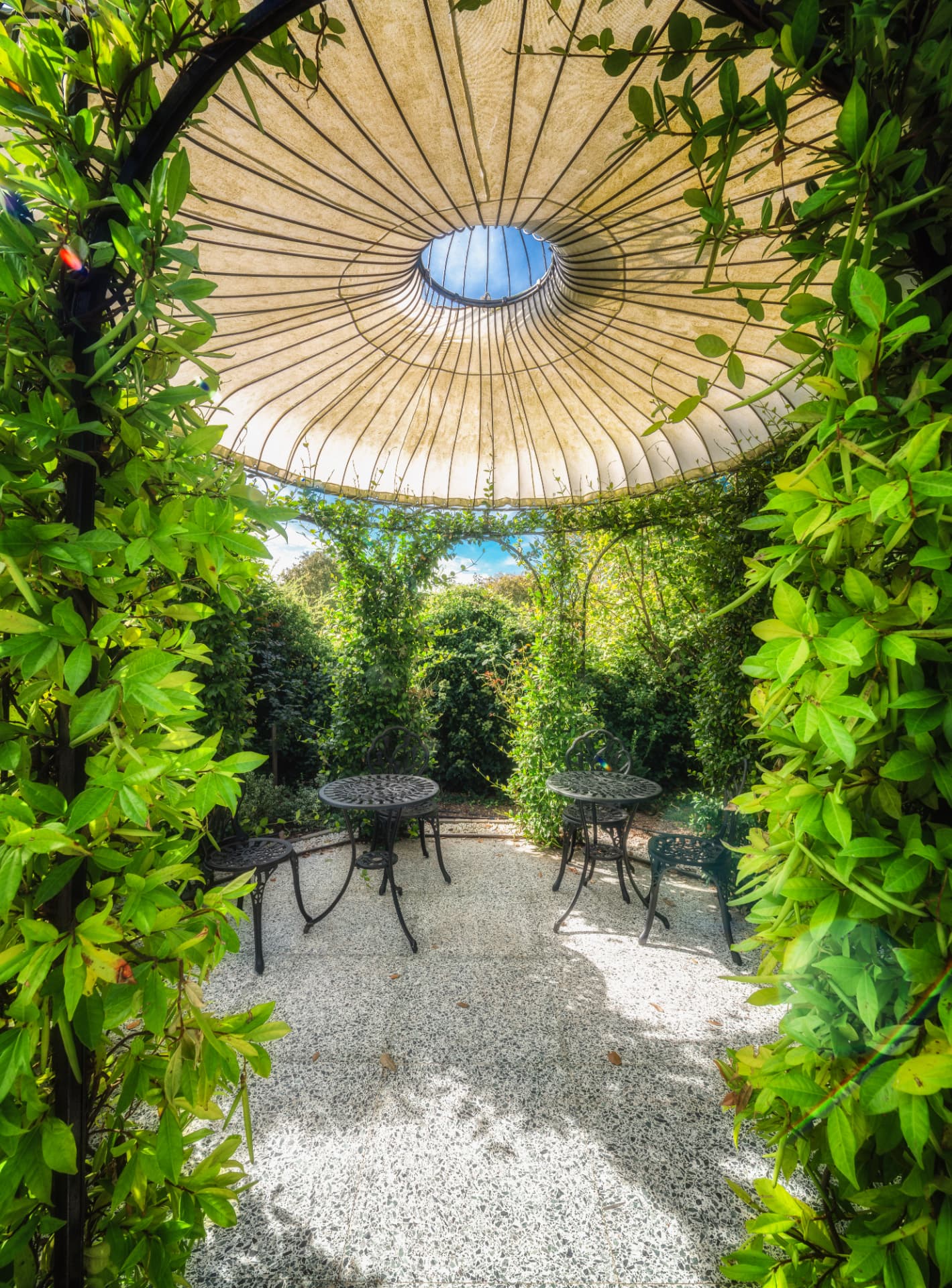Kiosque de jardin du Château de Crâche sous son grand parasol de toile, entouré de verdure