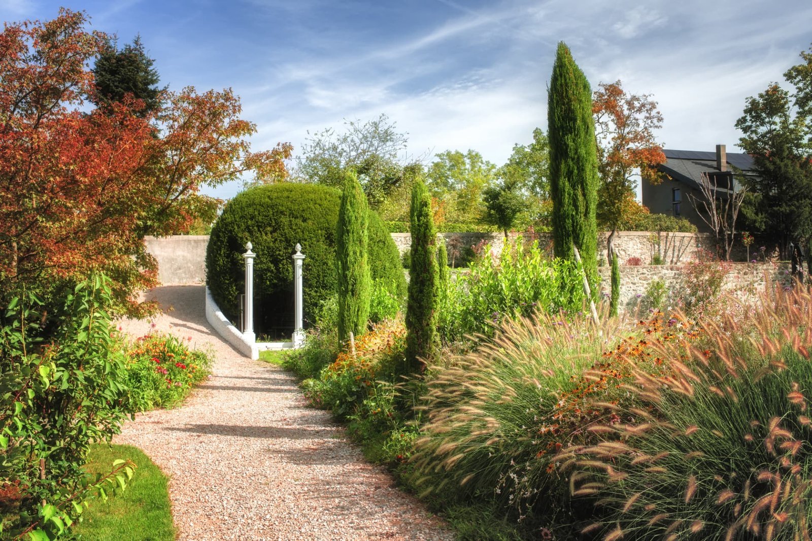 Allée de gravier du parc du Château de Crâche, cyprès et massifs fleuris près de Genève