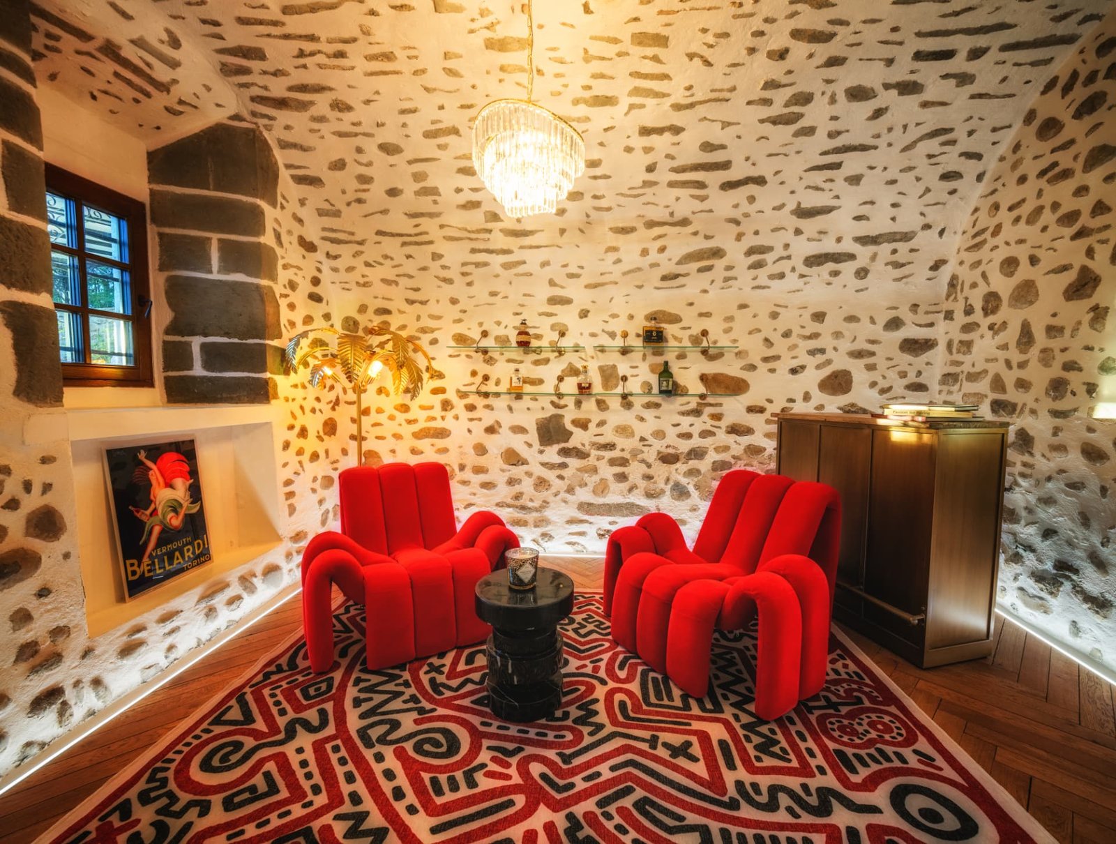 Fauteuils de velours rouge sous la voûte de pierre du Château de Crâche, lustre en cristal
